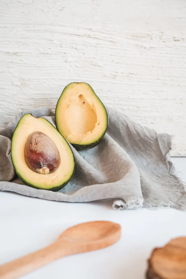 Cut avocado with a wooden spoon on a rustic surface