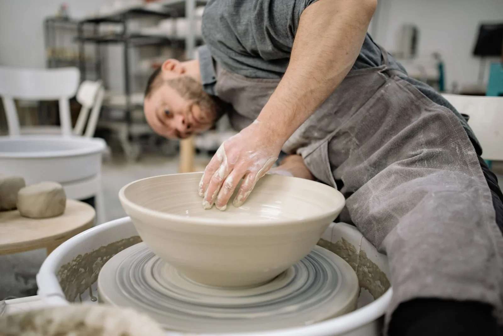 Hands shaping clay on a pottery wheel
